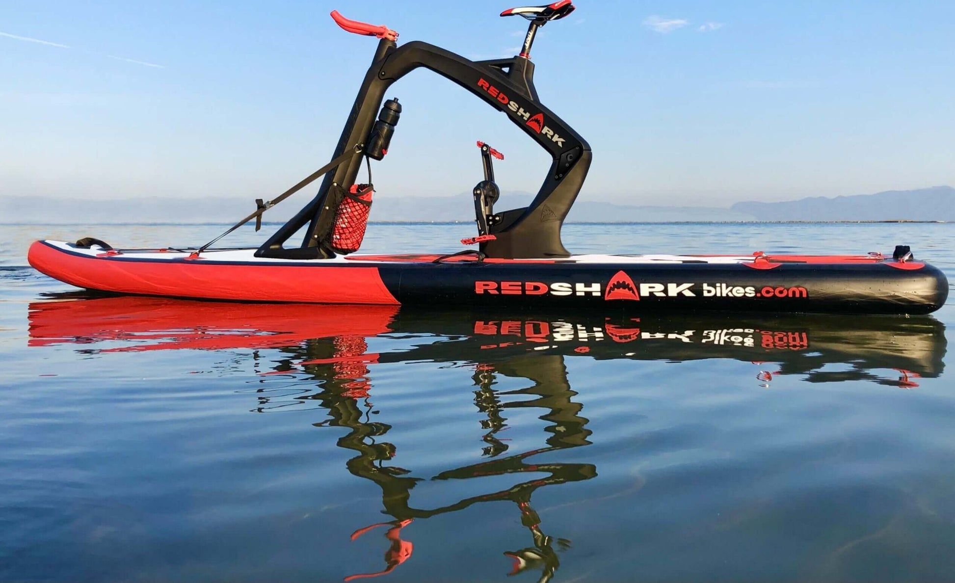 Red Shark water fitness bike on a lake, offering a unique workout experience with scenic nature views.