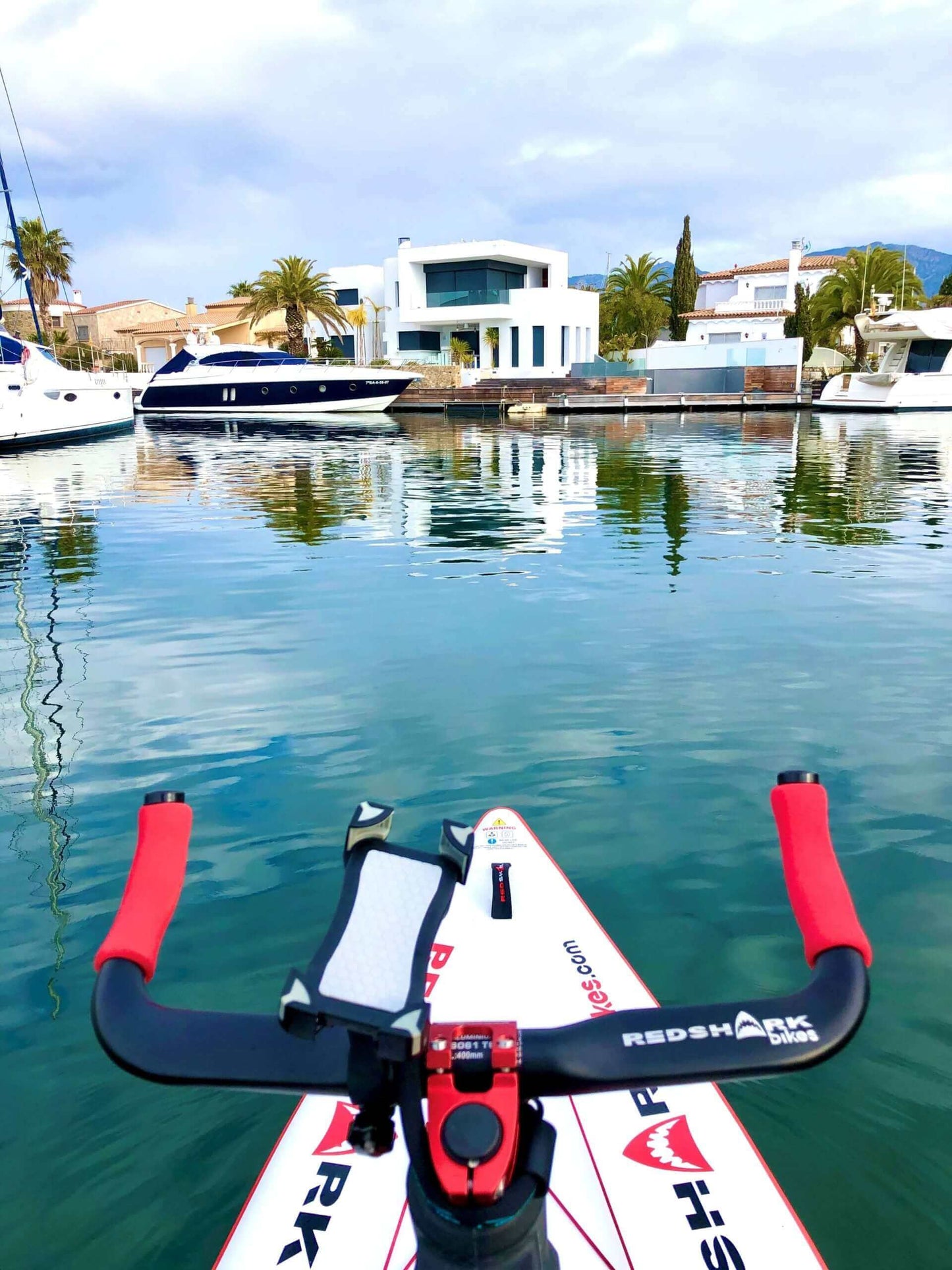 "Red Shark fitness board on water with scenic view of boats and houses"