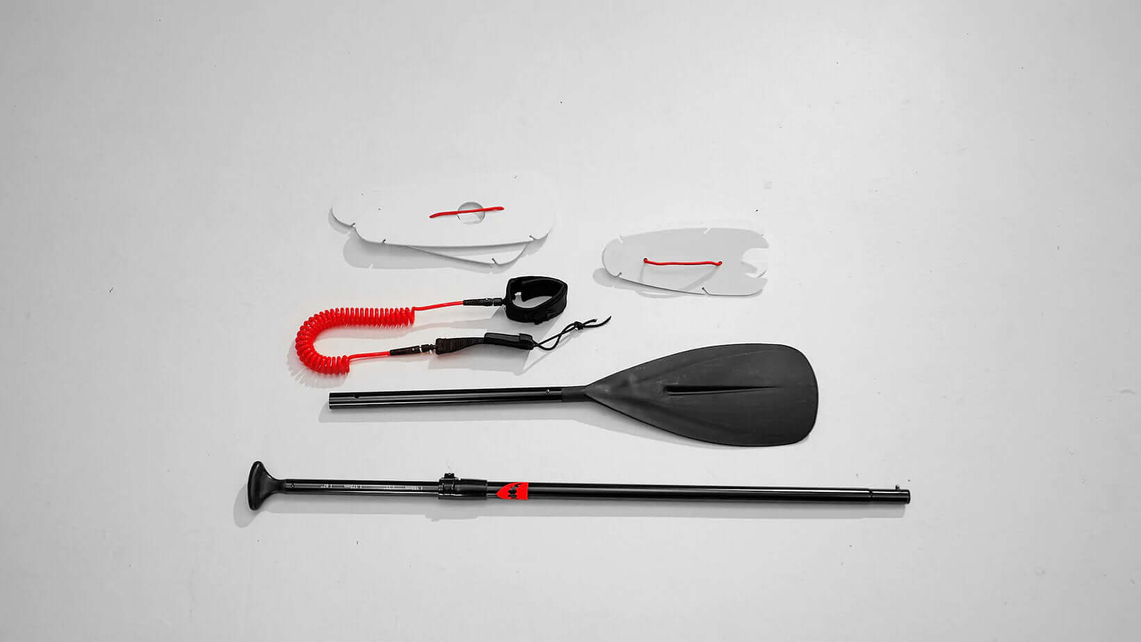 Red Shark Paddle SUP Kit with adjustable paddle, leash, and two hole covers on a white background.